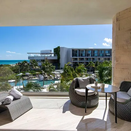Trs Coral Hotel (Adults Only) Cancun Interior photo The photo shows a luxurious outdoor balcony with a stunning ocean view. The balcony is spacious and features comfortable seating arrangements. There's a woven lounge chair with plush cushions and a small table with drinks, perfect for relaxing and en