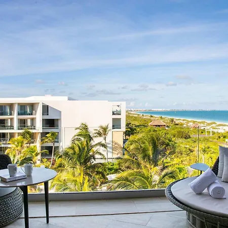 Trs Coral Hotel (Adults Only) Cancun Amenities photo The photo shows a balcony with a beautiful view of a tropical beach. The balcony is furnished with two wicker armchairs and a small round table. The chairs are gray and the table is white. There are two white mugs and a book on the table. The view fr