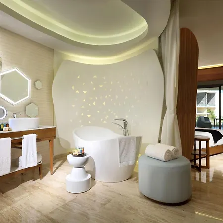 Trs Coral Hotel (Adults Only) Cancun Facilities photo The photo shows a luxurious and modern bathroom with a spa-like ambiance. The walls are a light beige with textured panels, and the floor is made of light-colored wood. 

The focal point of the bathroom is a large, white, oval-shaped bathtub with a s