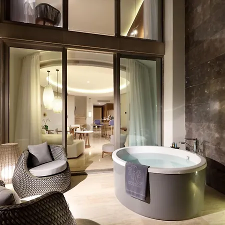 Trs Coral Hotel (Adults Only) Cancun Toilets photo The photo shows a luxurious bathroom with a modern design. The bathroom features a large, oval-shaped jacuzzi tub filled with light blue water. The tub is positioned in the foreground, slightly to the right of the center. 

To the left of the tub, th