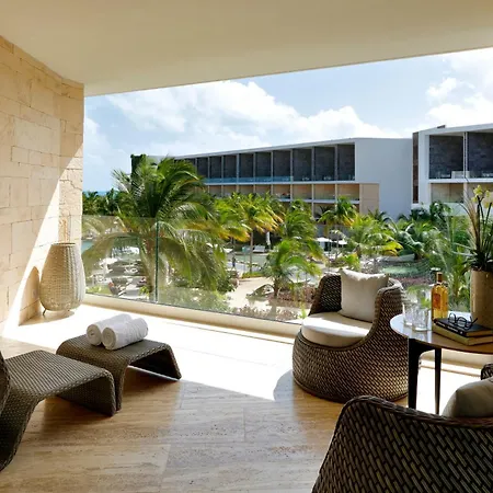 Trs Coral Hotel (Adults Only) Cancun Exterior photo The photo shows a bright and airy outdoor lounge area, likely part of a resort or hotel. The space is characterized by a large, open doorway or window that provides a stunning view of lush tropical scenery. 

The lounge features comfortable seating: 
